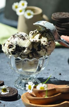 an ice cream sundae in a glass bowl on a table with cookies and spoons