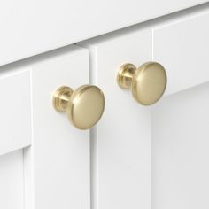 two white cabinets with gold knobs and handles on each cabinet door, one is closed