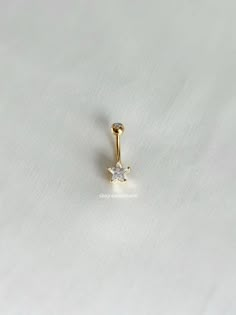 a gold nose ring with a single diamond in the middle on a plain white background