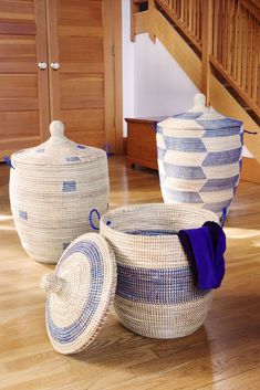 three woven baskets sitting on top of a hard wood floor next to a stair case