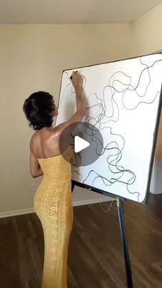 a woman in a yellow dress writing on a white board