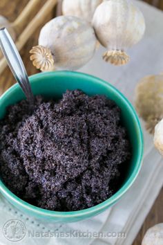 a blue bowl filled with brown stuff next to garlic and cloves on a table