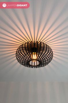 a light that is hanging from the ceiling in a room with white walls and shadows on the wall