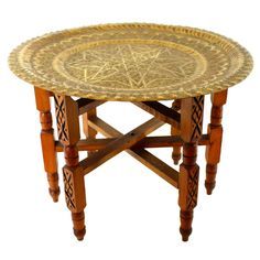 a round wooden table with an intricate design on the top and bottom, sitting against a white background