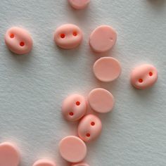 several pink buttons laying on top of a white surface with red dots in the middle