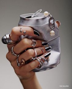 a woman's hand holding a metal can with rings on it and an open lid