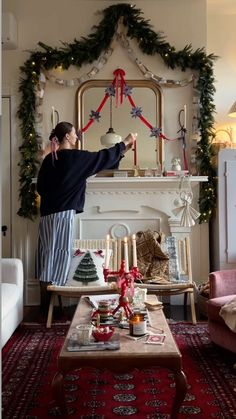 a woman standing in front of a fireplace with christmas decorations on the mantle and around her