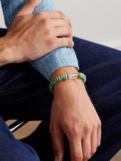 a man wearing a green bracelet sitting on a chair