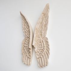 two white angel wings on a white surface with one wing folded back to the other