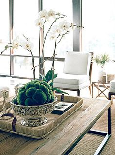 a living room filled with lots of furniture and flowers on top of a wooden table