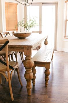 a dining room table with chairs and a bowl on it's centerpiece, in front of an open door