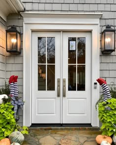 the front door is decorated for halloween with pumpkins and striped sock hats on it