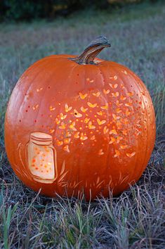 a carved pumpkin sitting in the grass with a mason jar on it's face