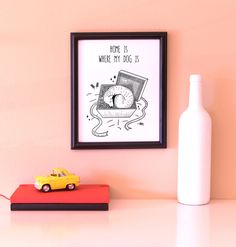 a yellow toy car sitting on top of a table next to a white bottle and framed poster