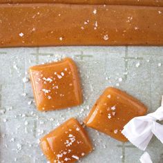 four pieces of caramel on a piece of parchment paper next to some salted sugar