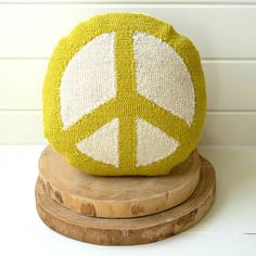 a yellow and white peace sign pillow sitting on top of a wooden stand