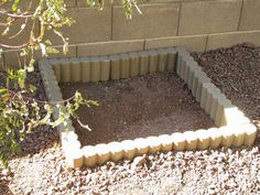 a garden bed made out of cinder blocks in the middle of a graveled area