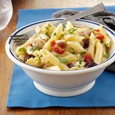 a white bowl filled with pasta salad on top of a blue napkin