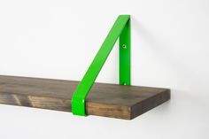 a wooden shelf with two green brackets on it