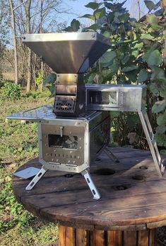 an outdoor stove sitting on top of a wooden table