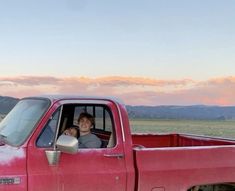 a man sitting in the bed of a red truck