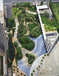 an aerial view of a city with lots of green trees and plants on the ground