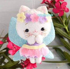 a white cat ornament hanging from a string with flowers on it's head