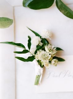 a bouquet of flowers sitting on top of a white paper with greenery around it