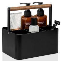 three bottles of soap and lotion in a black container with a wooden handle on the side