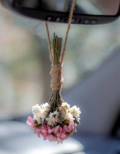 flowers are hanging from a rope in front of a car's rear view mirror