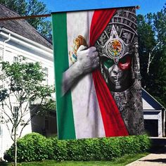 a large mexican flag hanging from the side of a house in front of a white building