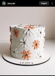 a close up of a cake on a white plate with orange and brown flowers in the frosting