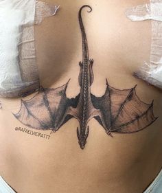 a woman's stomach with a tattoo of a dragon on the side and wings