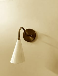 a wall mounted light on the side of a white wall in a room with beige walls