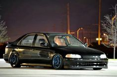 a black car with blue rims parked on the street