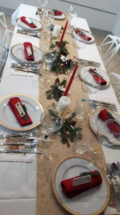 the table is set for christmas dinner with silverware and red napkins on it