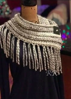 a mannequin wearing a black and white scarf with fringes on it's neck