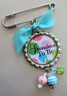 a bottle cap keychain with a blue bow and some beads on it that says grandma to be