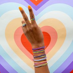 a woman's hand with bracelets on it and a heart painted on the wall behind her