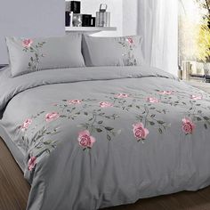 the comforter is made up with pink roses on grey sheets and pillowcases