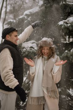 a man and woman standing in the snow with their hands out to each other,