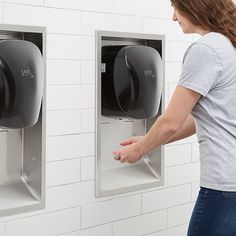 a woman standing in front of two urinals with their hands on the wall