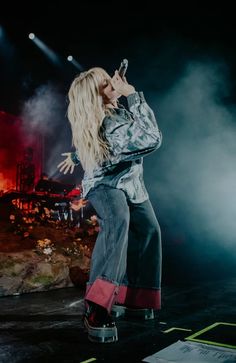 a woman standing on top of a stage while holding a cell phone to her ear