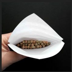 a hand holding a paper bag with some food inside of it on top of black background