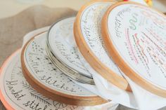 several embroidery hoops with writing on them sitting on top of a tablecloth covered surface