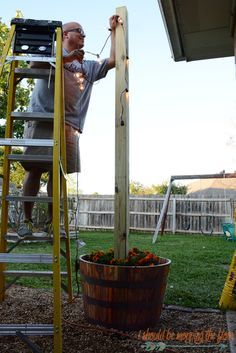 a man on a ladder working on a wooden structure