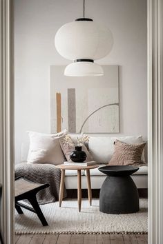 a living room with white walls and wooden flooring, two round tables on either side of the couch