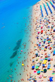 an aerial view of a beach with many umbrellas and people in the water on it