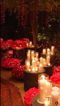 many candles are lit in front of red flowers