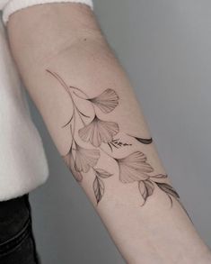 a woman's arm with flowers and leaves tattooed on the left side of her arm